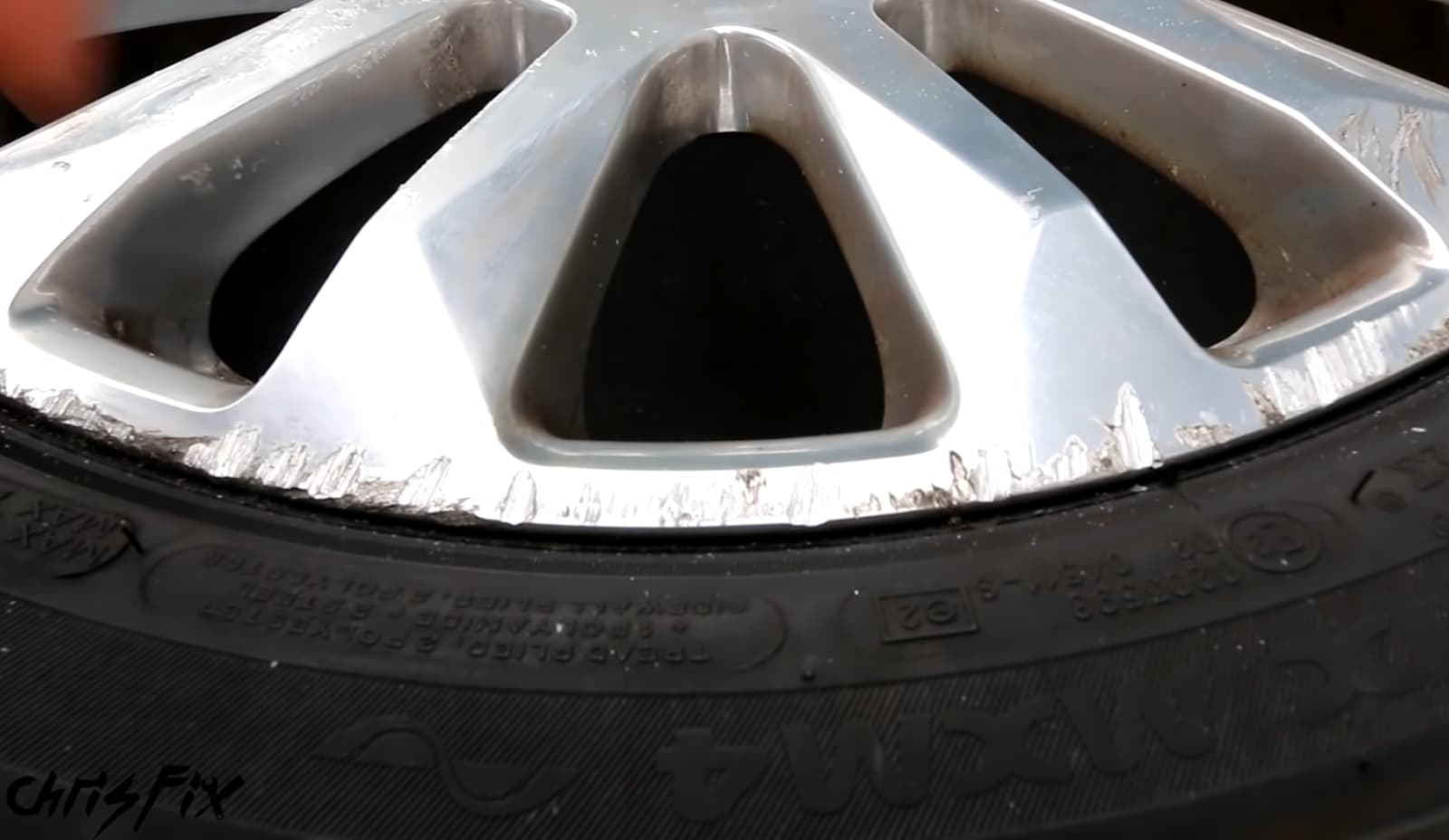 A close-up of a car wheel rim showing some wear and damage on it