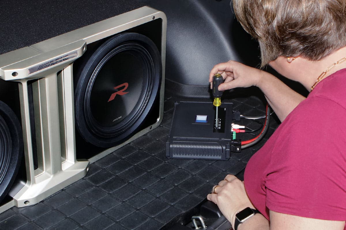 Woman setting up amplifier for subwoofer