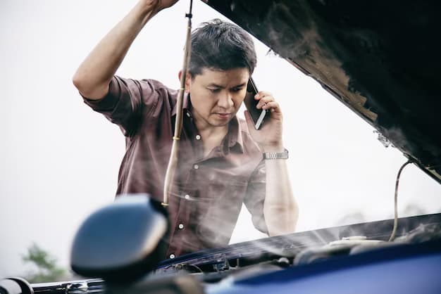 Man talking on the phone and holding the hood of a car